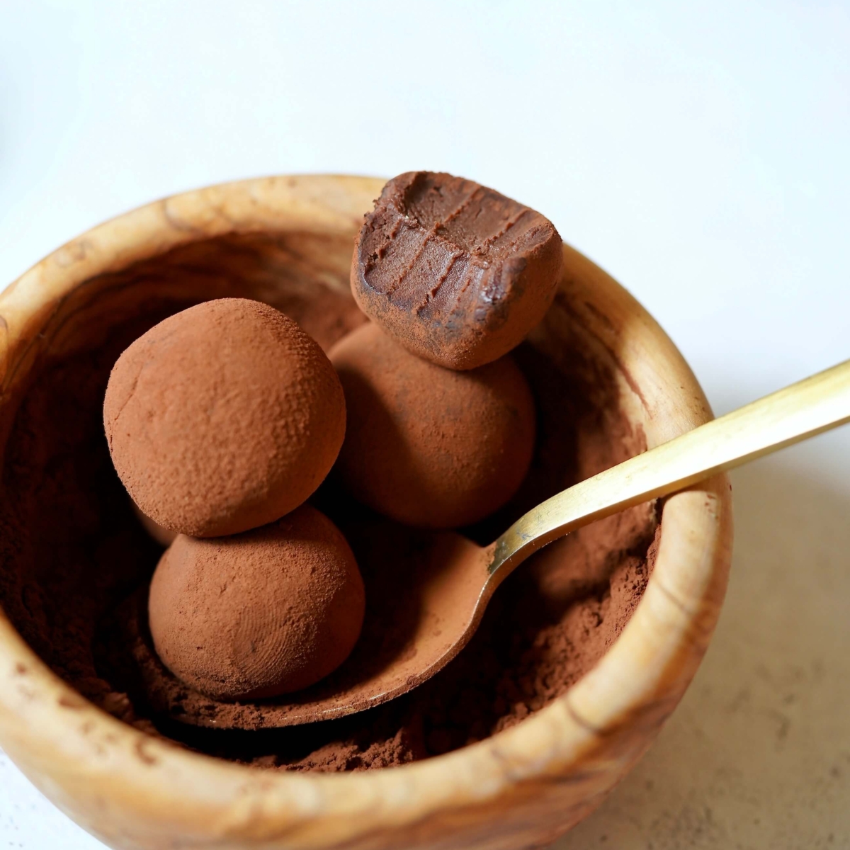 Chocolate truffle beside bulk measuring scoop with cocoa beans on